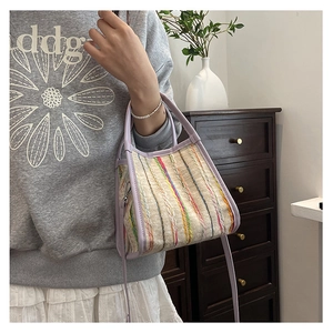 Detail der bunt gestreiften Web-Tasche mit lila Lederriemen in wohnlicher Umgebung