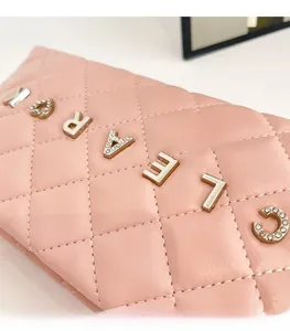 Detail of pink quilted leather handbag with rhinestone logo and chain strap accents
