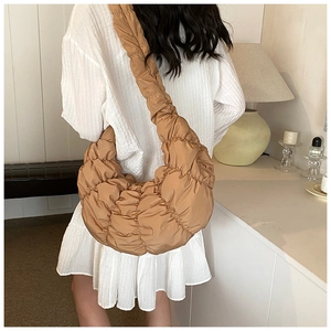 Detail der karamellfarbenen Croissant-Tasche mit weicher gesteppter Nylon-Textur