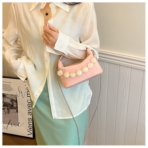Detail van roze crossbodytas met groot parelhandvat en zilveren kettingriem
