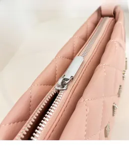Detailed shot of pink quilted leather bag featuring metal zipper and letter decoration