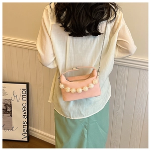Detail van roze crossbodytas met witte marmeren kralenketting en metalen schouderriem