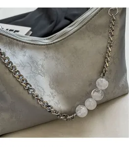 Detail of silver-grey shoulder bag with bamboo print texture and beaded chain strap