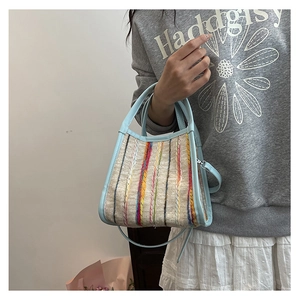Detailansicht der hellblauen Ledertasche mit bunten vertikalen Webstreifen-Mustern