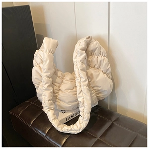 Detailaufnahme der beigen Croissant-Tasche mit weicher Steppung und Falten-Textur