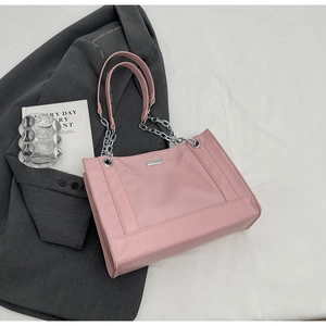 Detail der rosa Tragetasche mit Kunstlederstruktur, Silberkette und Metall-Logo-Plakette
