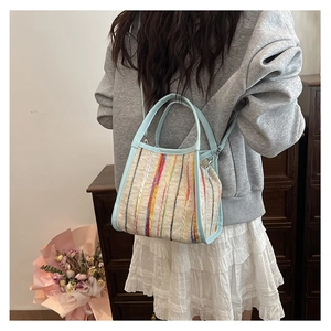 Détail d'un sac bandoulière en tricot à rayures colorées avec des poignées bleu clair