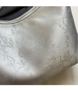 Close-up of lightweight silver shoulder bag featuring natural branch texture and metallic finish