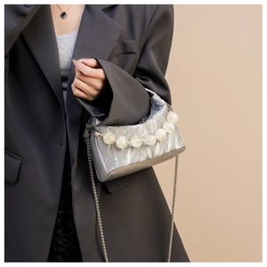 Detail van zilveren geplooide crossbodytas met matte kraalgreep en metalen schakelketting