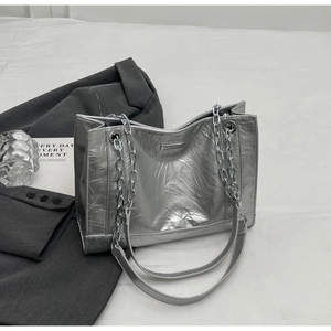 Detail der silbernen Metallic-Tasche mit Faltenstruktur und silberner Kette