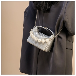 Detailopname van zilveren crossbodytas met grote witte kralen en metalen ketting
