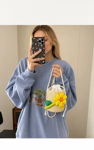 Close-up of beige woven bucket bag with yellow flower charm and drawstring closure