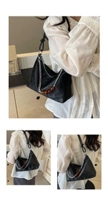 Close-up of black underarm bag with silver chain and amber bead details in a lifestyle setting