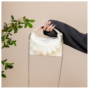 Detail van witte pluizige schoudertas met kralenhandvat en zilveren ketting