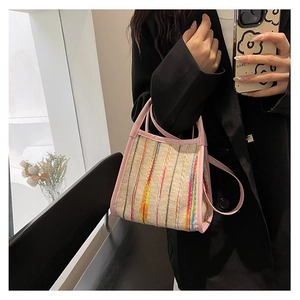 Detalle de bolso de mano tejido a rayas coloridas con asas de cuero rosa y correa de hombro