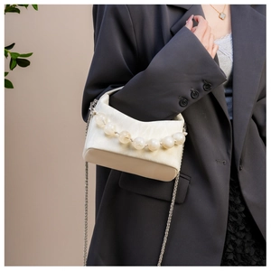 Detail van parelhandvat en kettingriem op een chique witte crossbodytas voor dames