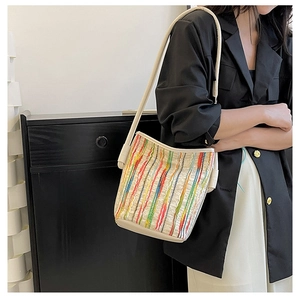 Détail d'un sac seau tissé à rayures colorées avec bandoulière crème et texture plissée