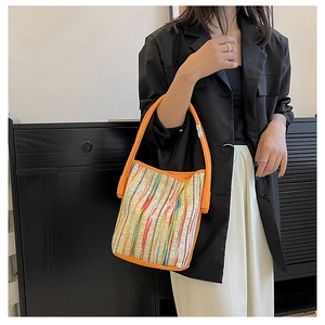 Détail du sac cabas tissé à rayures multicolores avec des anses en cuir orange vif
