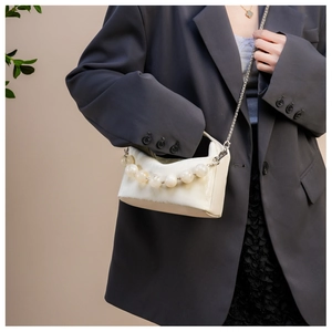 Detail van crème lederen tas met geel acryl kralen handvat en zilveren kettingriem