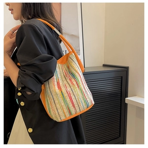Détail d'un sac seau en toile tissée à rayures colorées avec bandoulière en cuir orange