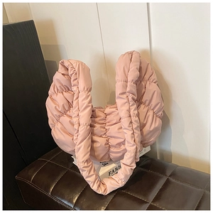 Nahaufnahme der rosa gesteppten Croissant-Tasche auf weißen Büchern bei weichem Licht