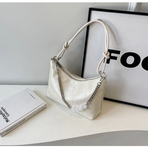 Detail of cream white shoulder bag featuring textured pattern and decorative beaded chain