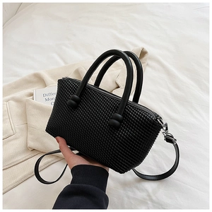 Gros plan du sac à main noir montrant la texture tissée gaufrée et les détails des anses