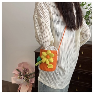 Detail of an orange woven bucket bag with large yellow flowers and drawstring liner