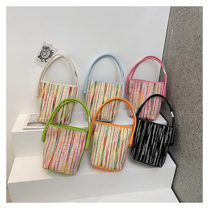 Détail de six sacs seaux en maille rayée colorée sur des supports de présentation