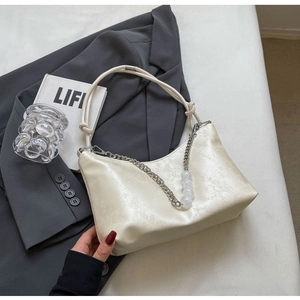 Detail of cream white underarm bag featuring jacquard texture and beaded chain strap