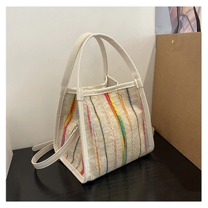 Detail der bunt gestreiften Stricktasche mit beigem Lederbesatz und Schultergurt