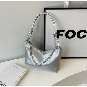 Detail of silver underarm bag featuring cracked texture leather and metallic chain bead strap