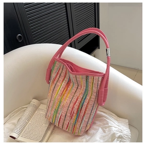 Close-up of colorful striped woven fabric and pink leather handle on a stylish tote bag
