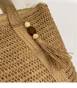 Detailed view of the woven straw tote bag featuring a wooden bead and tassel keychain