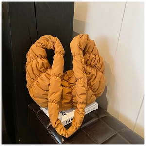 Nahaufnahme der ingwergelben, gesteppten Croissant-Tasche mit weicher Faltentextur