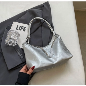 Detail of silver underarm bag with knot handle, branch texture and beaded chain decoration
