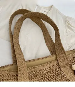 Close-up of khaki woven straw tote bag with wide handles and soft fabric lining