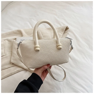 Détail d'un sac à main beige tressé avec poignée épaisse et bandoulière réglable