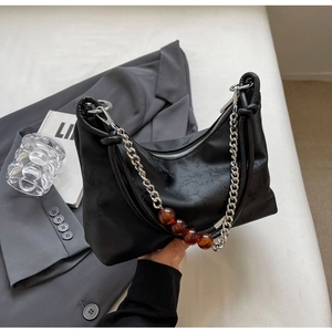 Detail of black leather underarm bag featuring silver chain and amber bead accents