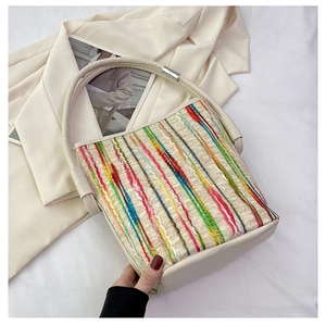 Détail des rayures tissées et des poignées en cuir crème sur un sac à main chic