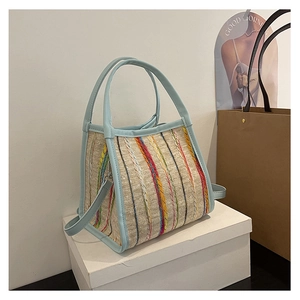 Detalle del bolso tejido a rayas de colores con ribete de cuero azul claro y herrajes