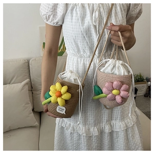 Detail of woven straw bucket bag featuring a large 3D flower and cotton rope strap