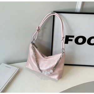 Detail of light pink shoulder bag featuring silver chain and white bead embellishments