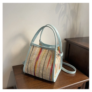 Detail der bunt gestreiften Web-Tasche mit hellblauen Lederriemen auf Holzoberfläche