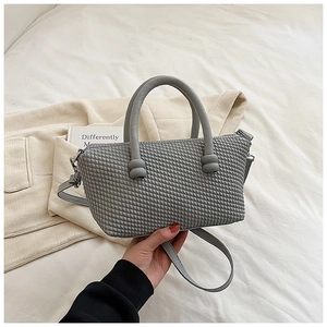 Détail du sac à main gris avec texture tissée, fermeture éclair et poignée élégante