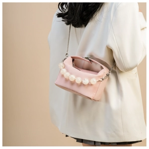 Detail van roze crossbodytas met elegant parelhandvat en zilveren kettingriem