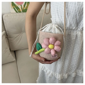 Close-up of pink woven flower bucket bag with a white drawstring lining and rope strap