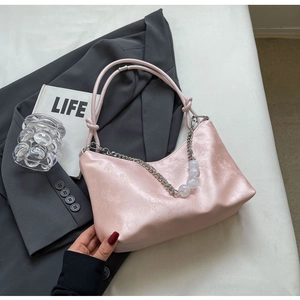 Detail of light pink shoulder bag with elegant beaded chain and retro textured finish