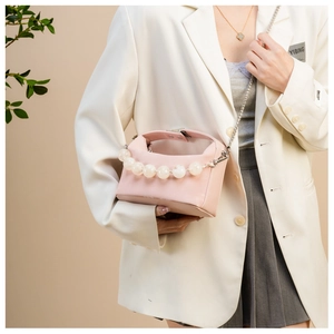 Detail van lichtroze crossbodytas met groot parelhandvat en zilveren kettingriem