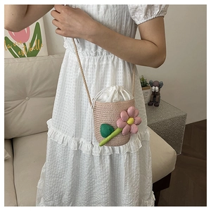 Detail of woven floral bucket bag with pink 3D flower and white drawstring closure
